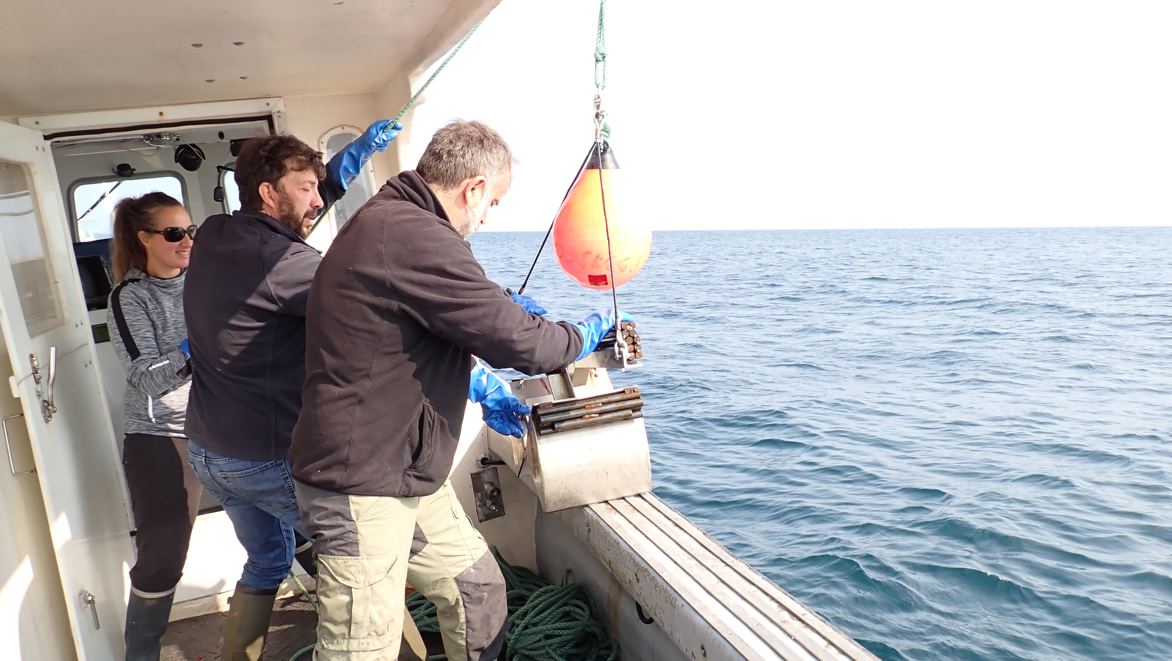 Mise à l’eau de la benne Van Veen par Laurent Chauvaud (premier plan), Yoann Busnot et Agathe Schmid pour échantillonner les habitats situés à plus de 30 m de profondeur © Lucas Pinsivy